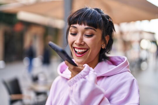Young woman smiling confident talking on the smartphone at street