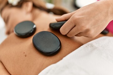 Obraz na płótnie Canvas Young latin woman having back massage session using hot stones