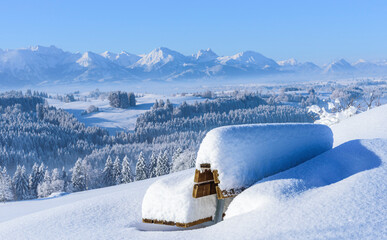 Idyllisch verschneite Bank an einem traumhaften Wintermorgen am bayerischen Alpenrand
