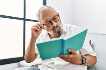 Fototapeta premium Senior grey-haired man reading book at home