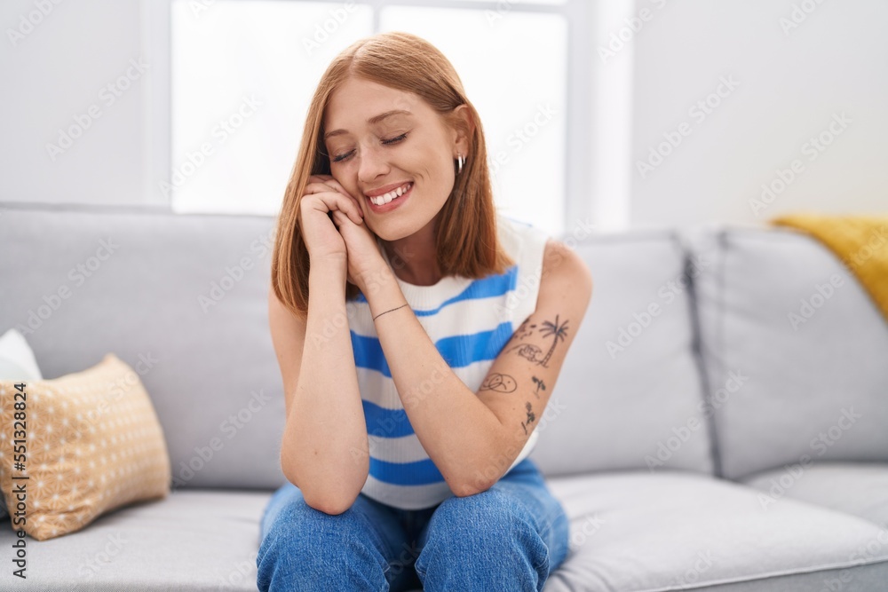 Sticker young redhead woman smiling confident sitting on sofa at home