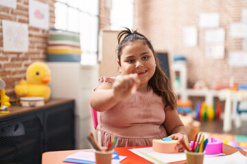 Plus size hispanic girl playing with toy holding color pencil at kindergarten