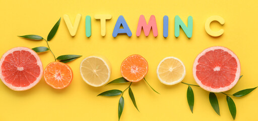 Text VITAMIN C and cut citrus fruits on yellow background
