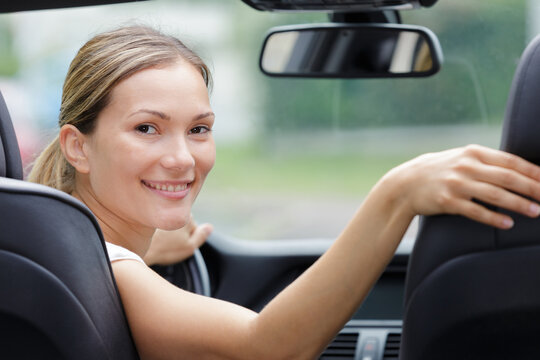 female driver smiling on the backseat for picture