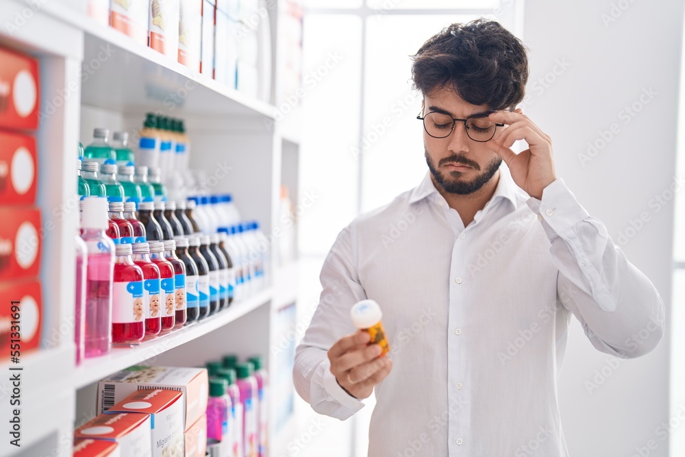 Wall mural Young hispanic man client holding pills at pharmacy