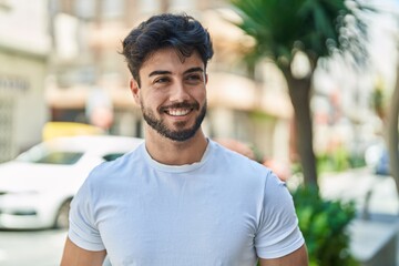 Young hispanic man smiling confident looking to the side at street