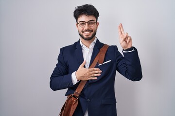 Hispanic man with beard wearing business clothes smiling swearing with hand on chest and fingers up, making a loyalty promise oath