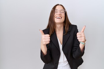 Beautiful brunette woman wearing business jacket and glasses success sign doing positive gesture...