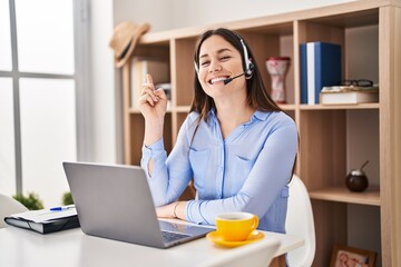 Young brunette woman wearing call center agent headset smiling happy pointing with hand and finger to the side