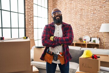 African american man working at home renovation happy face smiling with crossed arms looking at the...