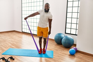 Young african american man smiling confident training with elastic band at sport center