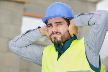 construction worker covering ears outdoors