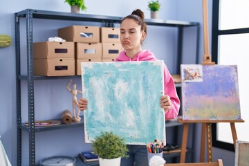 Young hispanic girl holding canvas depressed and worry for distress, crying angry and afraid. sad...