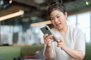 cheerful greeting exited smile asian woman hand holding smartphone with happiness big happiness face expression while checking good promotion or wonderful news while sitting in cafe co working space