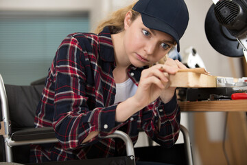 young lady in wheelchair preparing wood with sandpaper