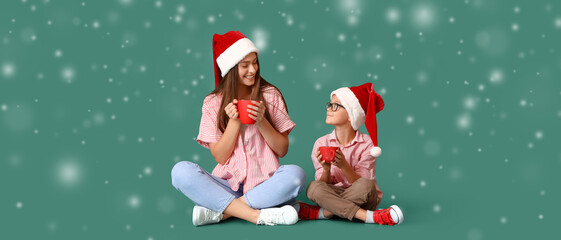 Little boy and his mother in Santa hats drinking hot chocolate on green background