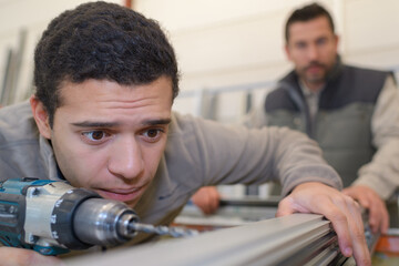 man drilling window frame nervous expression