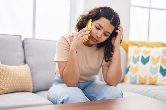 Young Woman Talking On The Smartphone With Worried Expression At Home