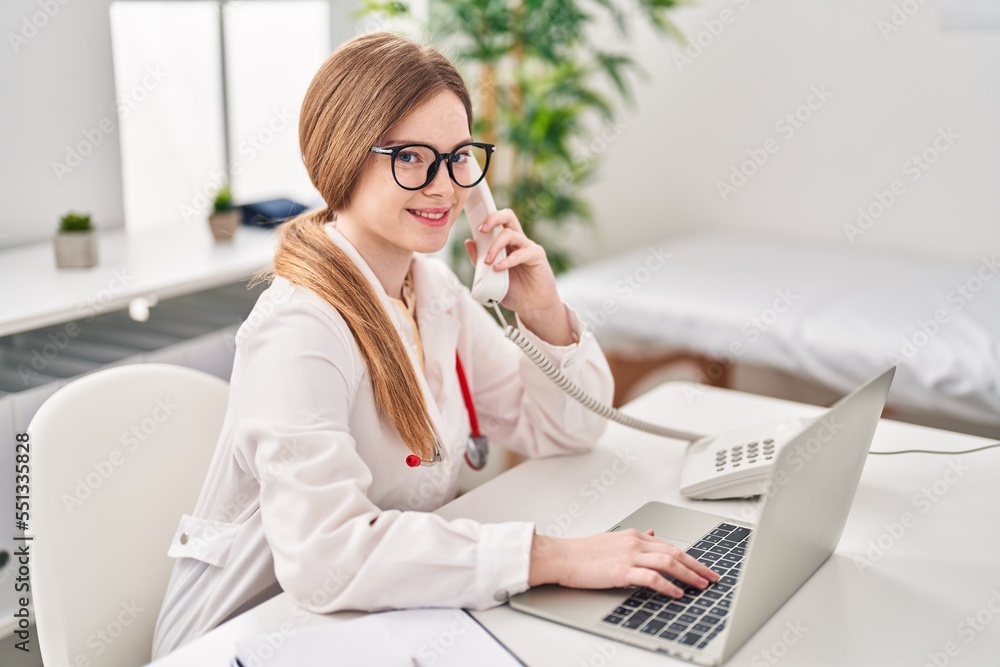 Canvas Prints Young blonde woman wearing doctor uniform talking on the telephone at clinic