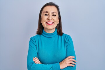 Obraz premium Middle age hispanic woman standing over isolated background happy face smiling with crossed arms looking at the camera. positive person.