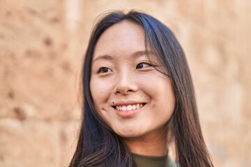 Fototapeta premium Young chinese woman smiling confident looking to the side at street