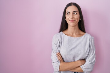 Obraz premium Young brunette woman standing over pink background smiling looking to the side and staring away thinking.