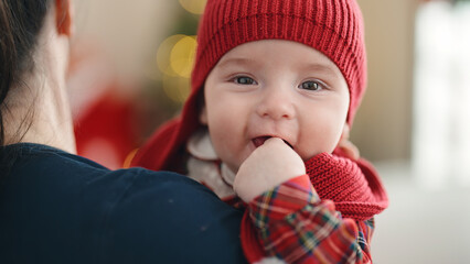 Adorable caucasian baby smiling confident relaxed on mother arms at home