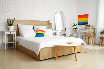 Interior of light bedroom with workplace, LGBT painting and pillow