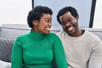 Obraz premium African american man and woman couple smiling confident sitting together at home