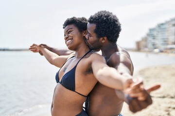 African american man and woman couple wearing swimsuit with arms open at seaside