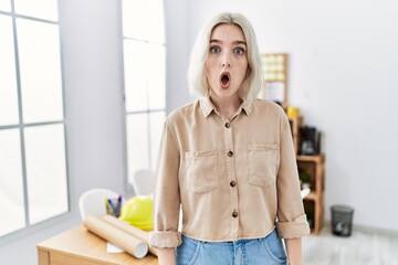 Young beautiful caucasian woman at construction office afraid and shocked with surprise expression,...