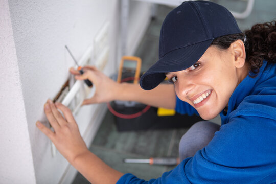 young brunette woman repairs an electric socket