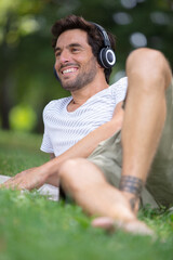 serene man resting in park and listening to music