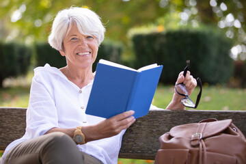 retired woman reading a book on the bench