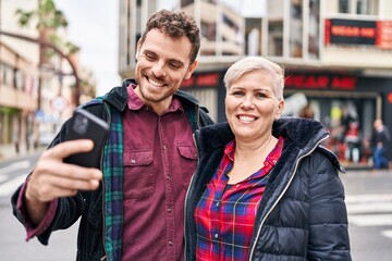 Mother and son smiling confident using smartphone at street