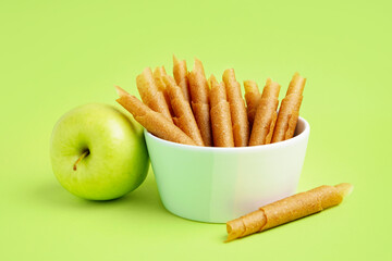 Bowl of tasty apple pastilles on green background