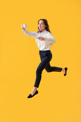 Fototapeta na wymiar Young assistant jumping on yellow background