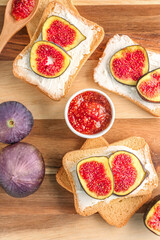 Obraz na płótnie Canvas Wooden board of tasty bruschettas with cream cheese and fresh figs, closeup