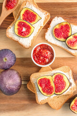 Wooden board of tasty bruschettas with cream cheese and fresh figs, closeup