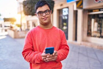 Down syndrome man smiling confident using smartphone at street