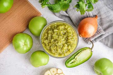 Bowl of tasty green salsa sauce with ingredients on light background - obrazy, fototapety, plakaty