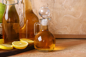 Obraz na płótnie Canvas Bottles of apple cider vinegar and lemon slices on color table, closeup