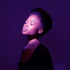 A young black woman with closed eyes in casual cloths on a purple background with copy space. A young woman with short haircut, mental health concept. High quality photo