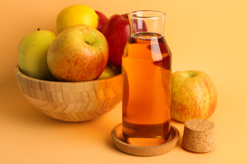 Bowl with ripe apples and bottle of fresh juice on color background
