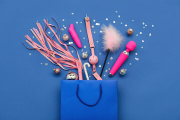 Shopping bag with sex toys and Christmas decor on blue background