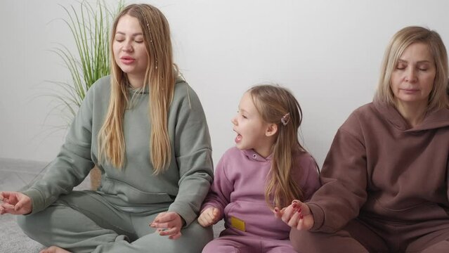 Home Yoga. Impatient Girl. Family Relax. Calm Mother And Grandmother Meditating Sitting Floor While Curious Girl Pulling Mom Light Room Interior.