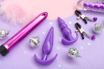 Sex toys and Christmas decor on lilac background, closeup