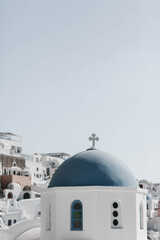 Beautiful blue dome of a church on Santorini island, Greece. The church stands against the backdrop of the sea and islands, near a beautiful flowering plant. High quality photo