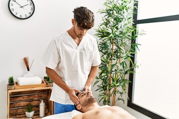 Two hispanic men therapist and patient having facial massage at beauty center