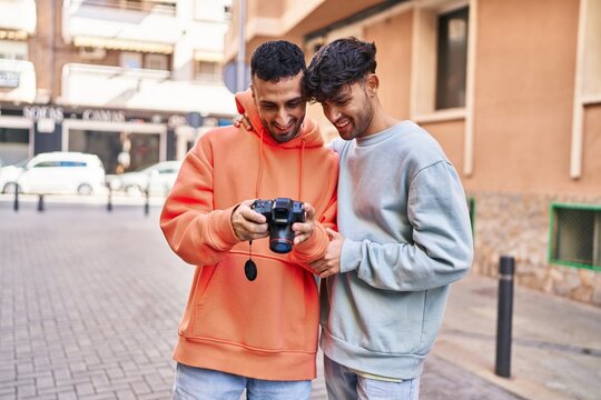 Two man couple using professional camera at street